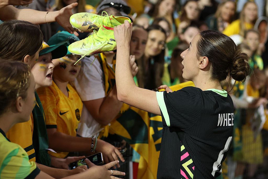 NEWCASTLE, AUSTRALIA - APRIL 07: Clare Wheeler of Australia signs her boots before giving them to a fan during the International Friendly match between Australia Matildas and Korea at McDonald Jones Stadium on April 07, 2025 in Newcastle, Australia. (Photo by Scott Gardiner/Getty Images)
