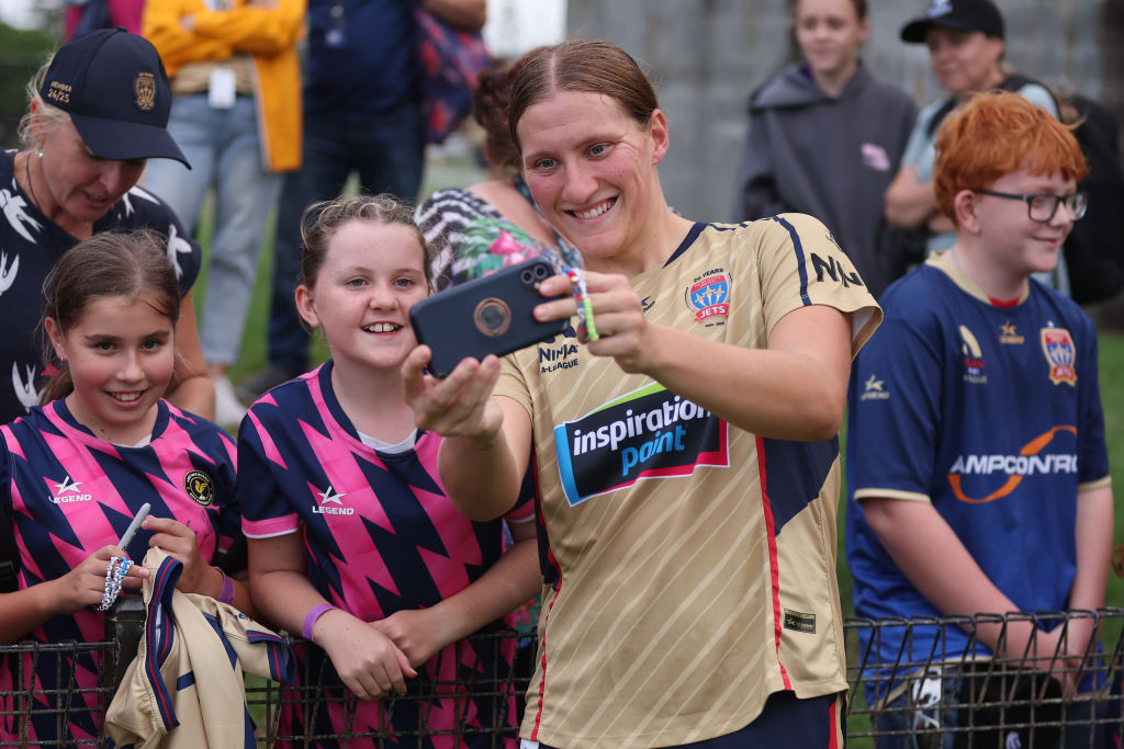 NEWCASTLE, AUSTRALIA - MARCH 08: Natasha Prior of the Jets takes a selfie with a fan during the round 18 A-League Women's match between Newcastle Jets and Sydney FC at No.2 Sportsground, on March 08, 2025, in Newcastle, Australia. (Photo by Scott Gardiner/Getty Images)